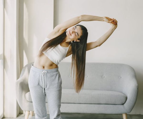 Smiling woman stretching her arms in a bright living room